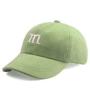 Détail d'une casquette vert clair avec broderie 'm' blanche et texture en tissu de coton