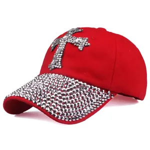 Dettaglio cappello rosso con croce di strass argentati e visiera decorata con borchie