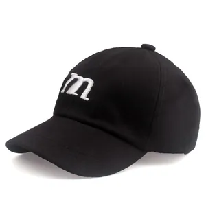 Détail de la broderie blanche de la lettre m sur le devant de la casquette noire