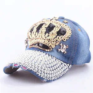 Detail of denim baseball cap with gold crown sequins, skull studs and pearl brim