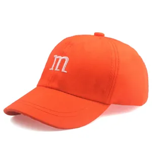 Détail de la casquette orange en coton avec broderie m blanche et coutures précises