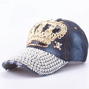 Detail of denim baseball cap with gold crown sequins, skull accent, and pearl brim