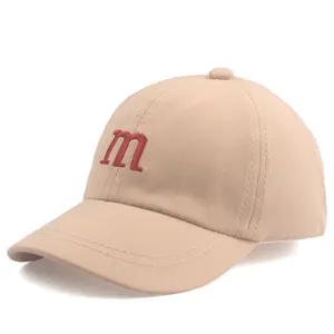 Détail de la broderie lettre m rouge sur casquette beige pour enfant avec coutures