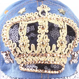Detailed embroidery of gold crown and black sequins on blue denim baseball cap surface