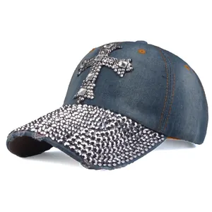 Dettaglio del cappello da baseball in denim vintage con croce di strass e visiera usurata