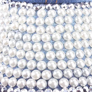 Detailed macro shot of faux pearls and rhinestones on light blue denim baseball cap surface