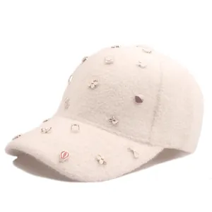 Detail der cremeweißen Plüsch-Baseballkappe mit bunten Emaille-Anhängern und weicher Textur