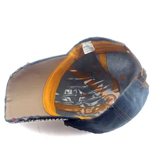 Detail view of denim baseball cap interior featuring a yellow sweatband and cotton tag