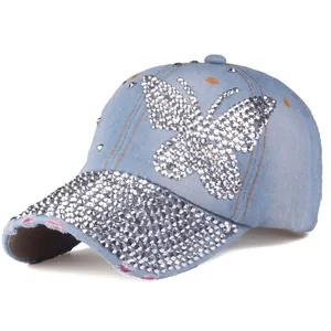 Dettaglio del cappello da baseball in denim azzurro con farfalla di strass e visiera