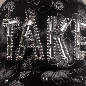 Macro view of black baseball cap with floral glitter print and TAKE rhinestone detail