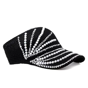 Detail of black knitted sun visor with elegant white pearls and sparkling rhinestone trim