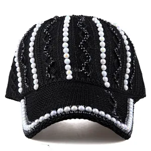 Détail d'un chapeau de soleil noir avec perles blanches et rayures perlées