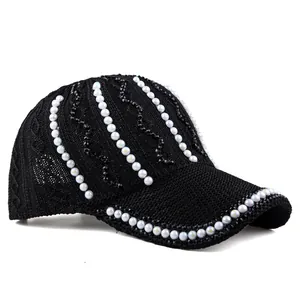 Détail d'une casquette en maille noire avec perles blanches et sequins brillants