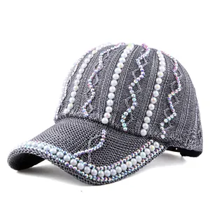 Détail d'une casquette en maille grise ornée de strass brillants et perles blanches