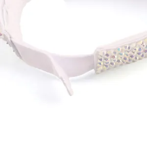 Detail van de verstelbare witte zonneklep met klittenbandsluiting en kleurrijke strass