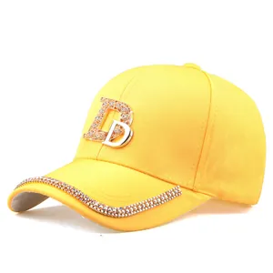 Détail de la casquette de baseball jaune avec logo DB en strass et bordure brillante