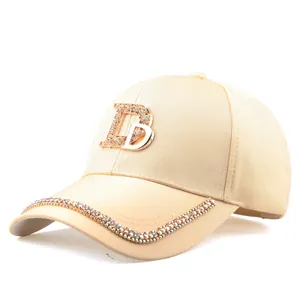 Détail de casquette beige avec logo DB en métal brillant et bordure en strass colorés