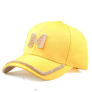 Detailansicht der gelben Baseballkappe mit Strass-M und glitzernden Akzenten am Schirm