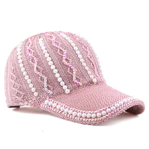Détail d'une casquette rose en maille avec perles blanches et strass colorés brillants
