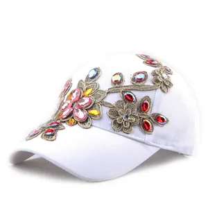 Detailed close-up of a white baseball cap featuring vibrant floral rhinestone embroidery