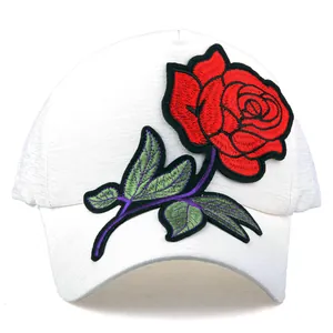 Gros plan d'une broderie de rose rouge sur une casquette de baseball blanche en tissu fin