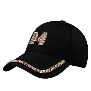 Detail einer schwarzen Baumwoll-Baseballkappe mit Strass-M-Logo und glitzerndem Schirm