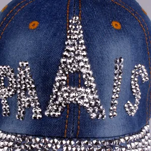 Macro detail of rhinestone PARIS lettering and studs on navy blue denim baseball cap