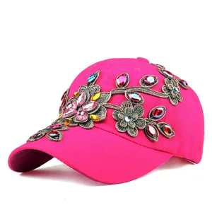 Detail of rose pink baseball cap with intricate gold floral embroidery and colorful rhinestones