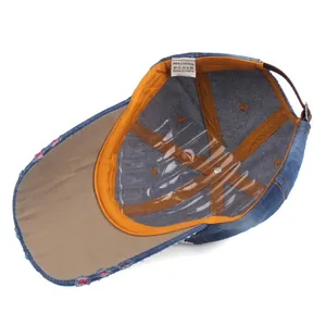 Internal view of denim baseball cap showing orange lining and 100% cotton fabric label