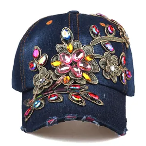 Detailed close-up of colorful rhinestones and gold floral embroidery on denim baseball cap