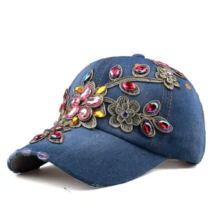 Detailed close-up of blue denim baseball cap with floral embroidery and colorful rhinestones