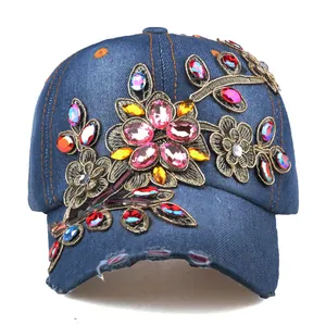 Close-up of denim baseball cap with colorful rhinestone flowers and frayed brim details