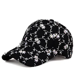 Close-up of black baseball cap with intricate white floral embroidery and colored rhinestones