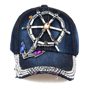 Macro detail of nautical helm and anchor rhinestone embellishments on denim baseball cap