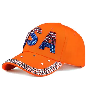 Close-up of sparkling USA rhinestones and silver studs on an orange denim baseball cap