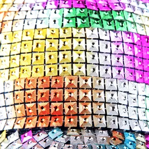 Macro detail of rainbow sequin fabric with square metallic studs and colorful textures