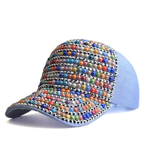 Détail de la casquette en denim bleu avec perles colorées et clous argentés
