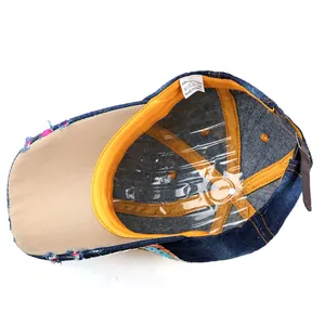 Detail view of denim baseball cap interior featuring orange sweatband and adjustable buckle