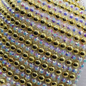 Detailed close-up of golden metallic beads and AB iridescent rhinestones on white fabric
