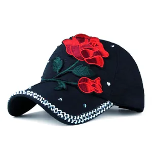 Detail of red rose embroidery and sparkling rhinestones on a black cotton baseball cap