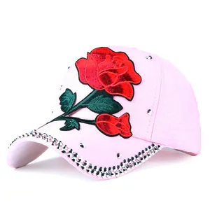 Close-up of pink cotton baseball cap with red rose embroidery and silver studs