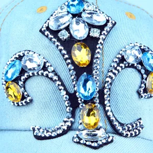 Denim baseball cap with fleur-de-lis patch featuring rhinestones and colorful crystals