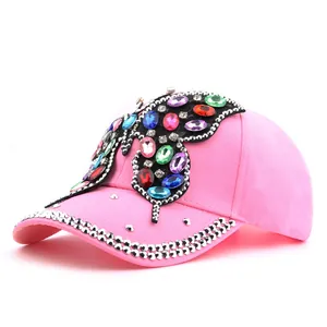 Détail de casquette rose avec grand papillon en strass colorés et bordure ornée de bijoux