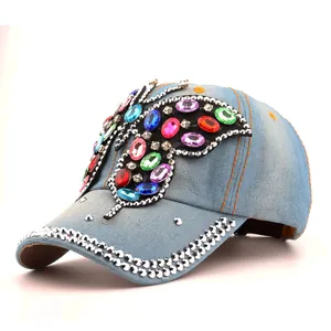 Détail d'une casquette en denim bleu clair ornée d'un grand papillon en strass colorés