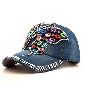 Gros plan du papillon en strass et rivets argentés sur la casquette en jean