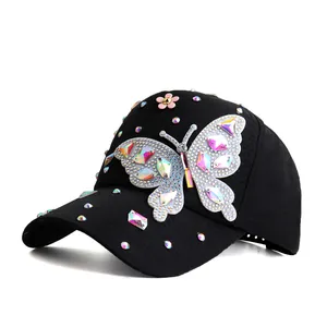 Détails d'une casquette noire ornée d'un papillon étincelant en strass colorés brillants