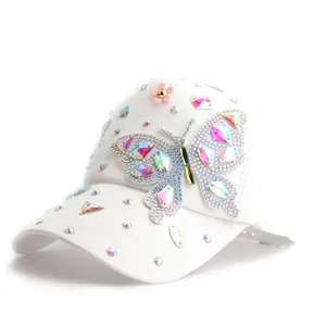 Détail d'une casquette blanche avec papillon en strass colorés et petite fleur en 3D