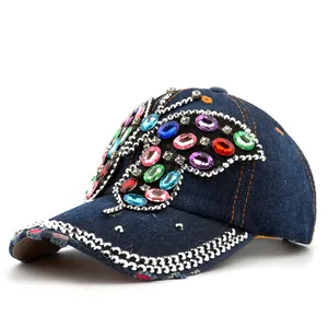 Détail d'une casquette en jean bleu ornée d'un grand papillon en pierres précieuses colorées