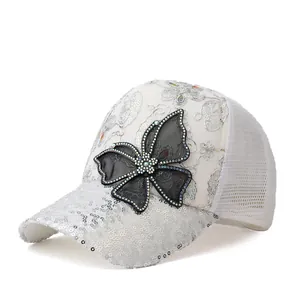 Detail van witte mesh pet met zilveren lovertjes en zwarte strik met strassteentjes