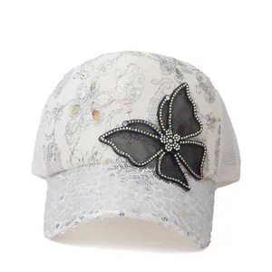 Witte dames honkbalpet met zilveren pailletten, kanten bloemen en strass vlinderdasje